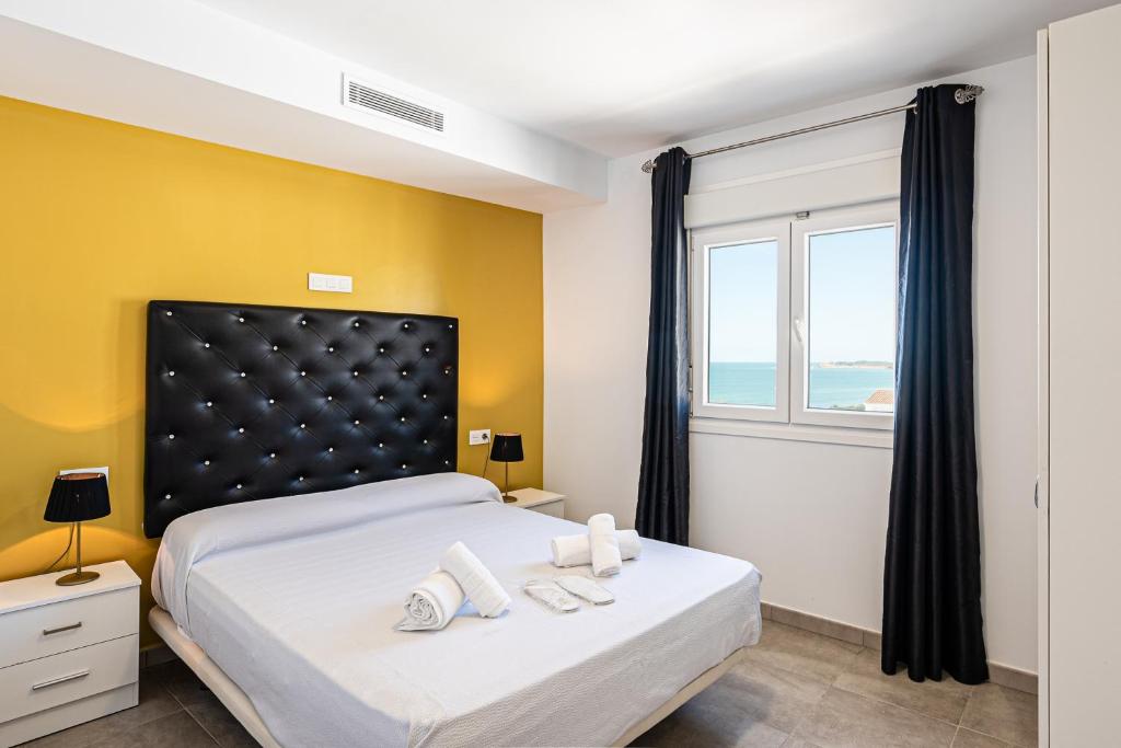 a bedroom with a large bed with yellow walls and a window at Apartamentos Turísticos La Boutique del Mar in Conil de la Frontera