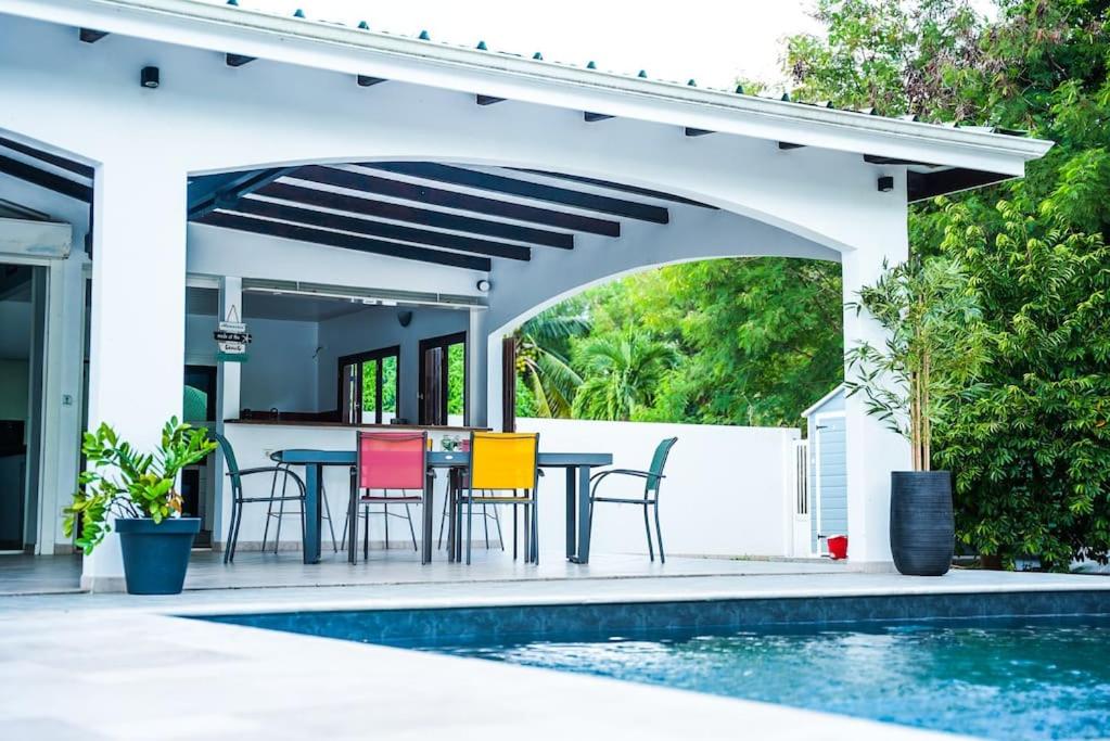a patio with a table and chairs next to a pool at Magnifique villa avec piscine in Sainte-Anne