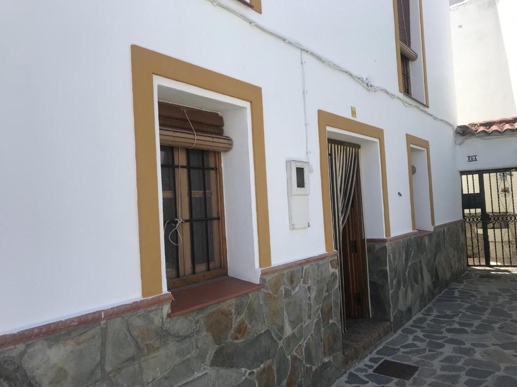 um edifício branco com duas janelas e uma porta em CASA PETRA : Bonita casa rural en Yunquera em Yunquera