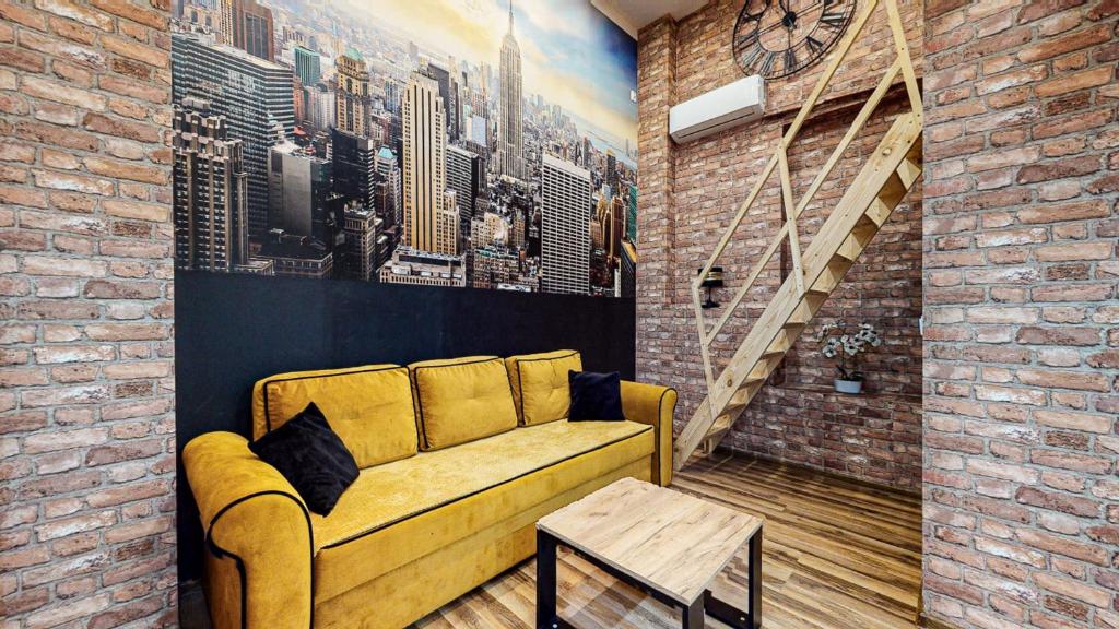 - un salon avec un canapé jaune et un mur en briques dans l'établissement LOFT MANHATTAN DE LUX CENTRUM DWORCOWA, à Bytom