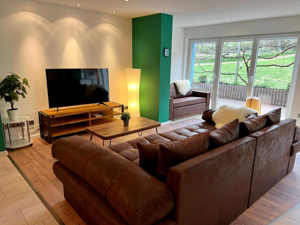 a living room with a brown couch and a flat screen tv at JUNIPRO Apartments Haustadt in Beckingen