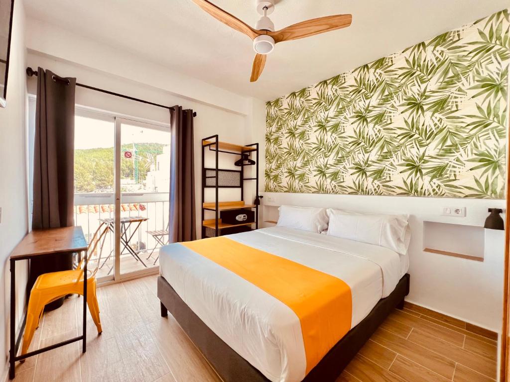 サンタ・エウラリア・デス・リウにあるNanit Rooms Ibiza Hostalのベッドとバルコニー付きのホテルルーム