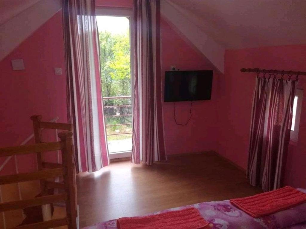 een slaapkamer met roze muren en een raam en een bed bij Dupleks apartmani "Šumadija" Bogutovačka Banja in Bogutovac