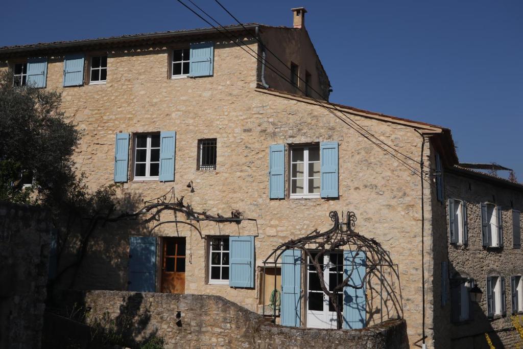 un viejo edificio de ladrillo con persianas azules. en Beautiful house with swimming pool in the historic center, en Forcalquier