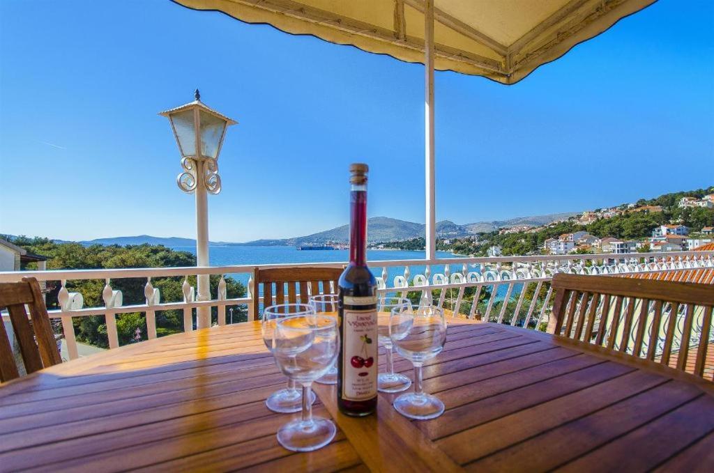 uma garrafa de vinho sentada numa mesa de madeira com copos em Three bedroom apartment with amazing sea view em Trogir