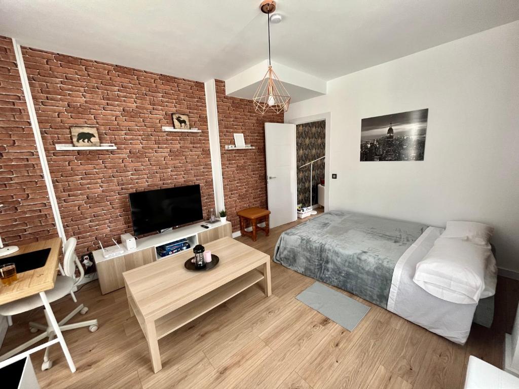 a bedroom with a brick wall and a bed and a tv at Apartamento en Cartama Concepción esquina calle toril 1A in Cártama