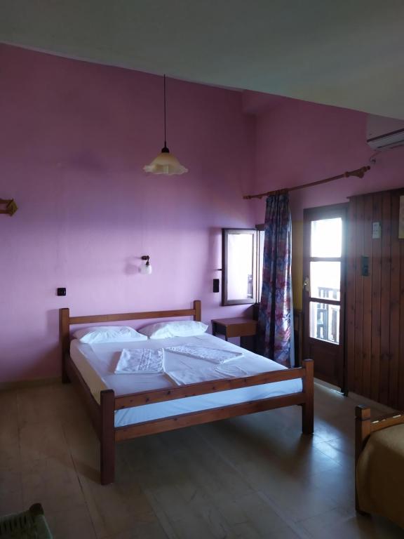 sypialnia z dużym łóżkiem i różową ścianą w obiekcie Triple studio room in Mylopotamos Beach w mieście Tsagarada