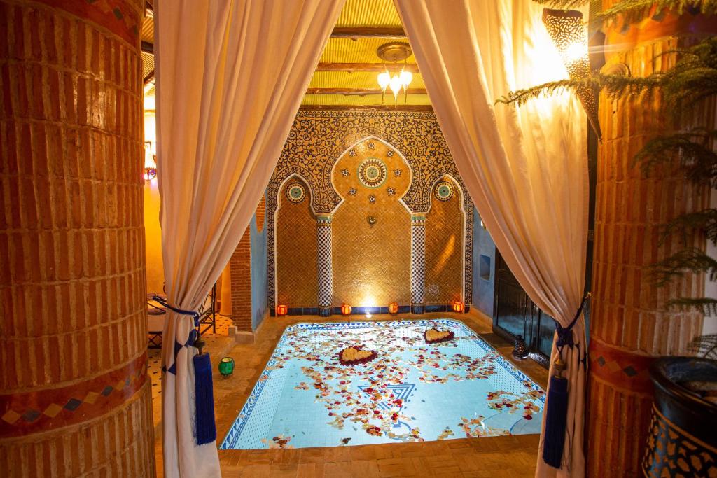 Cama grande en habitación con cortinas y flores en Riad Christina, en Marrakech