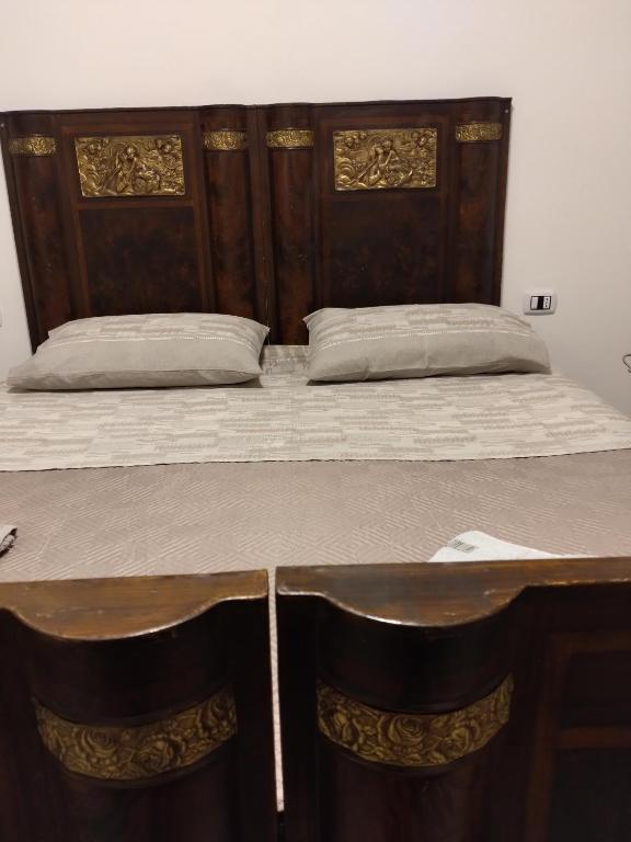 a large bed with a wooden headboard and a table at Settesette6 in Barghe