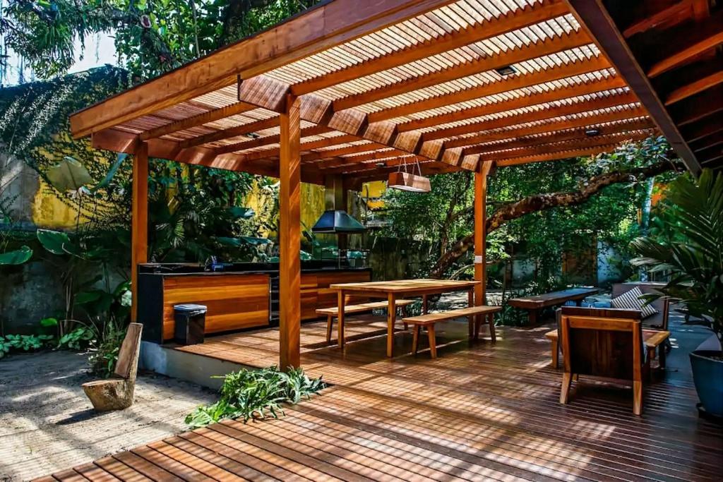 a wooden pergola with a wooden table and benches at Casa Tubarão - A Melhor in Camburi