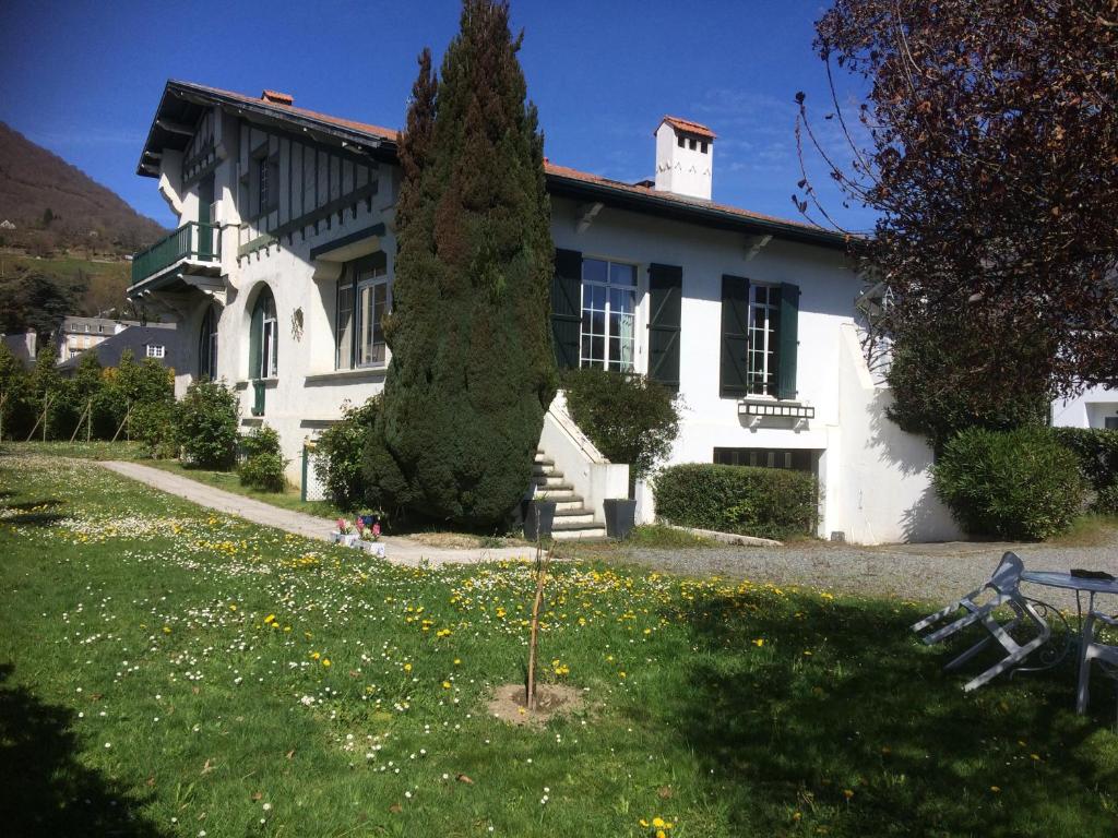 une maison blanche avec un arbre dans la cour dans l'établissement Maison Etcheverria, à Argelès-Gazost