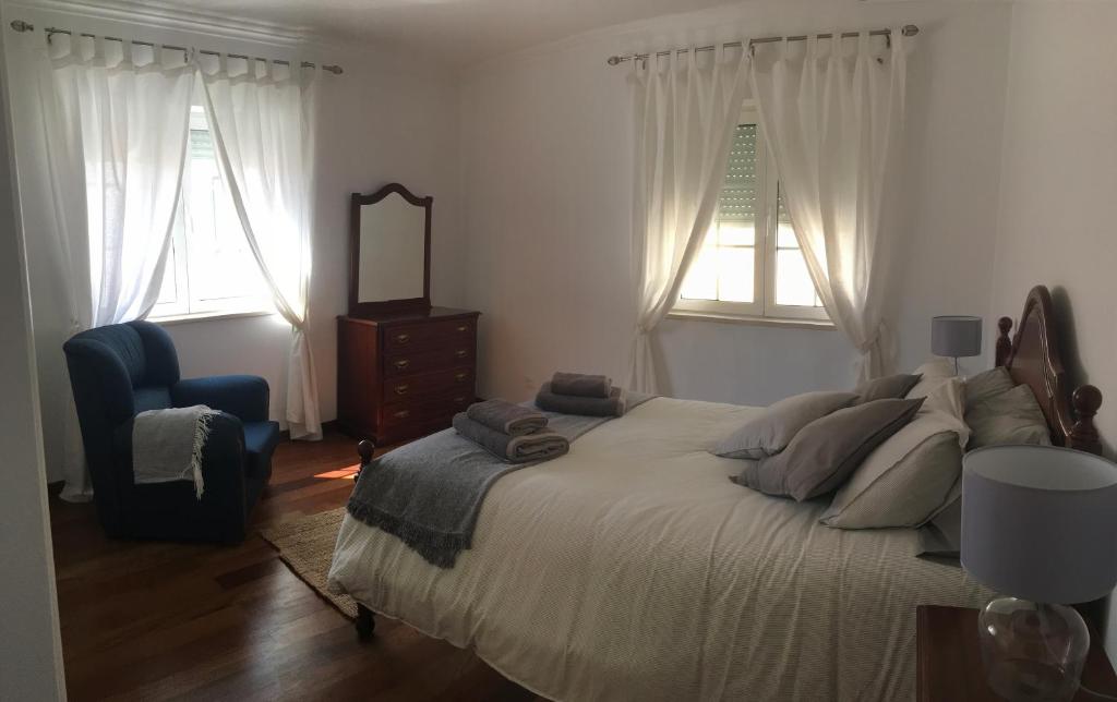 um quarto com uma cama, um espelho e uma cadeira em Maré Alta em Sines