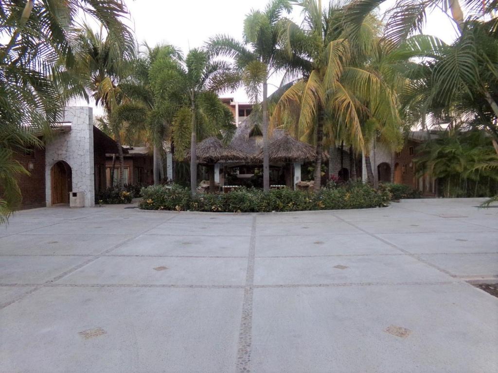 une maison avec des palmiers en face d'une cour dans l'établissement Hotel Casa de Lirio Diamante, à Acapulco