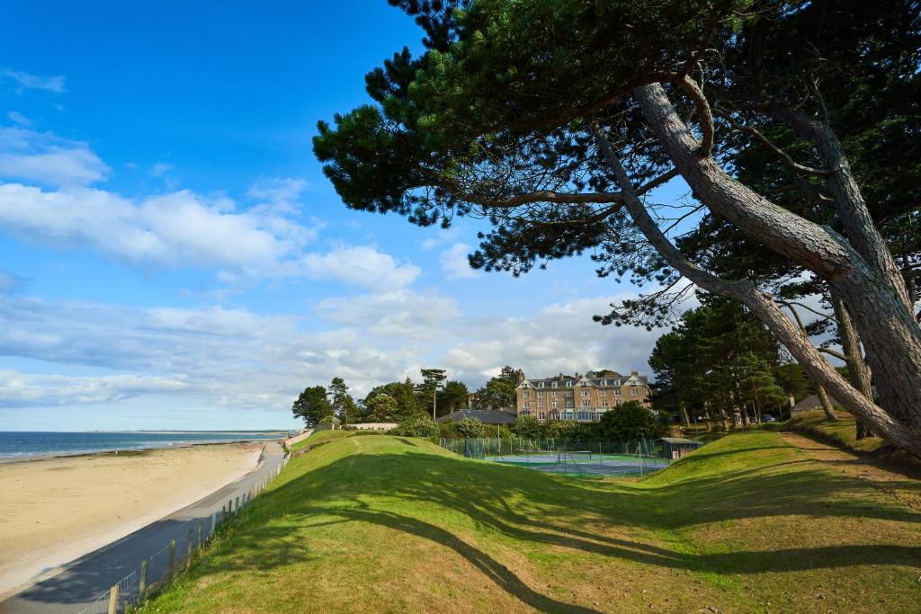a beach scene with trees and grass at Golf View Hotel & Spa in Nairn