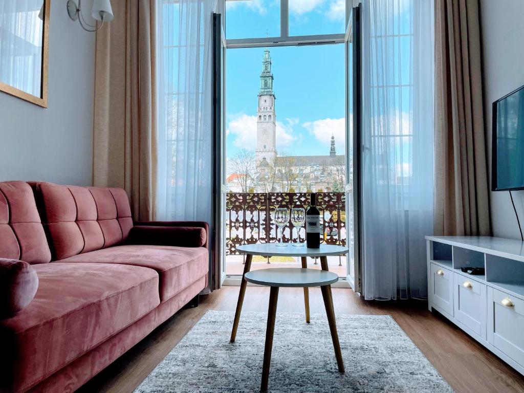 チェンストホヴァにあるBiały Kruk Apartamenty vis-a-vis Jasnej Góryのリビングルーム(ピンクのソファ、窓付)