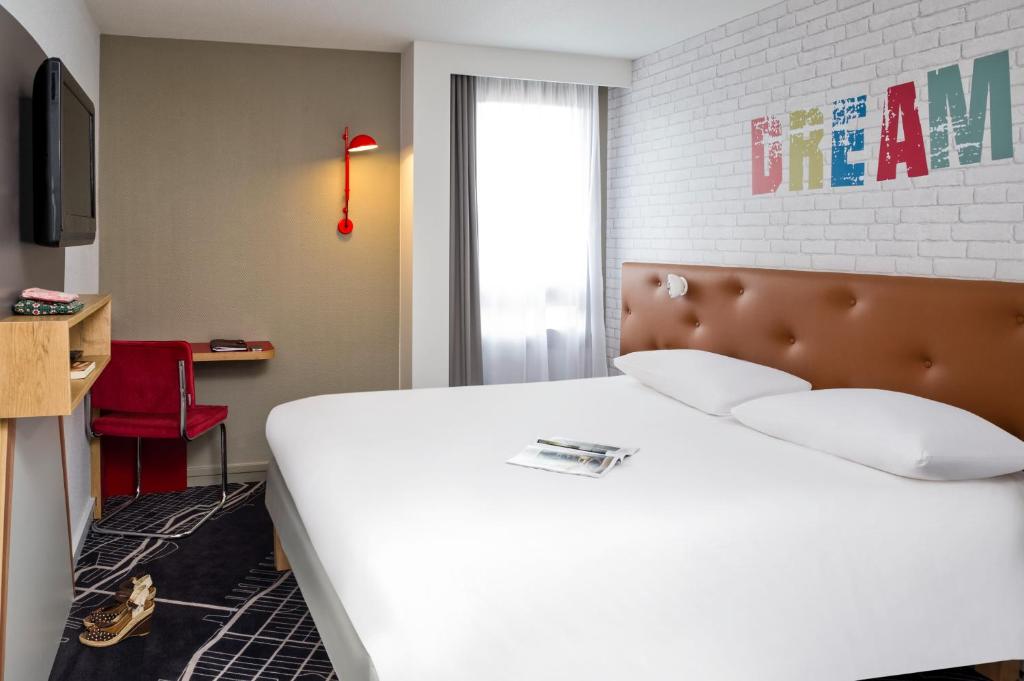 une chambre avec un grand lit blanc et une fenêtre dans l'établissement ibis Styles Chartres Métropole, à Chartres