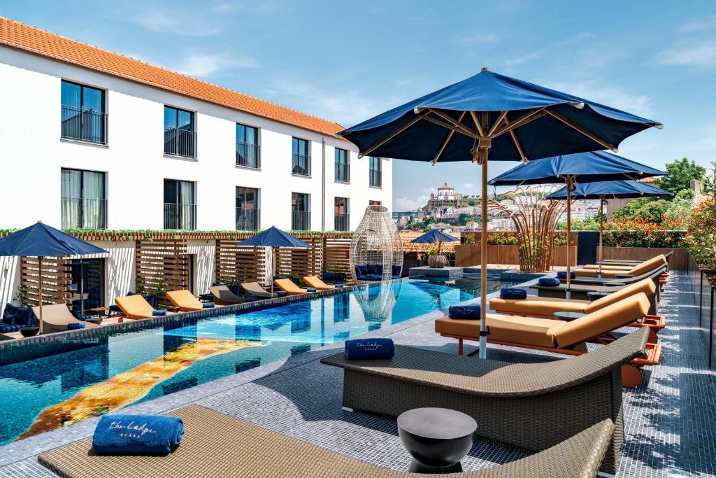 a hotel with a pool with lounge chairs and umbrellas at The Lodge Hotel in Vila Nova de Gaia