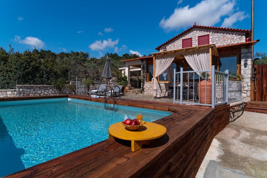 a pool with a table on a deck next to a house at Sea Rock Villa Rodos in Archangelos