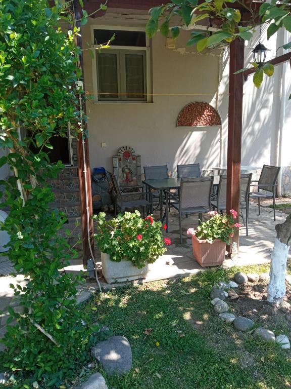 a patio with a table and chairs and flowers at Sofia's Garden in Nea Peramos