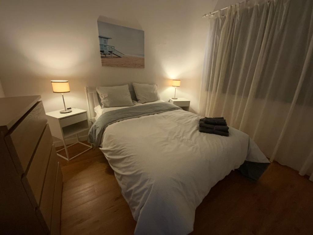 a bedroom with a white bed with two lamps at La Garita Bay Apartments in La Garita