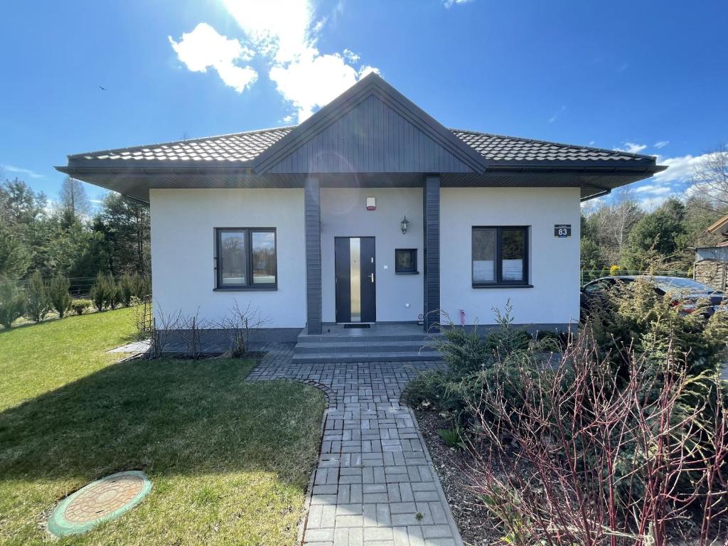 a small white house with a pathway at Dom na skraju lasu in Arciechow