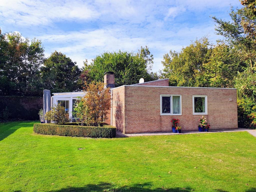 a brick house with a green lawn in front of it at Wunderschönes Ferienhaus in Strandnähe in Retranchement