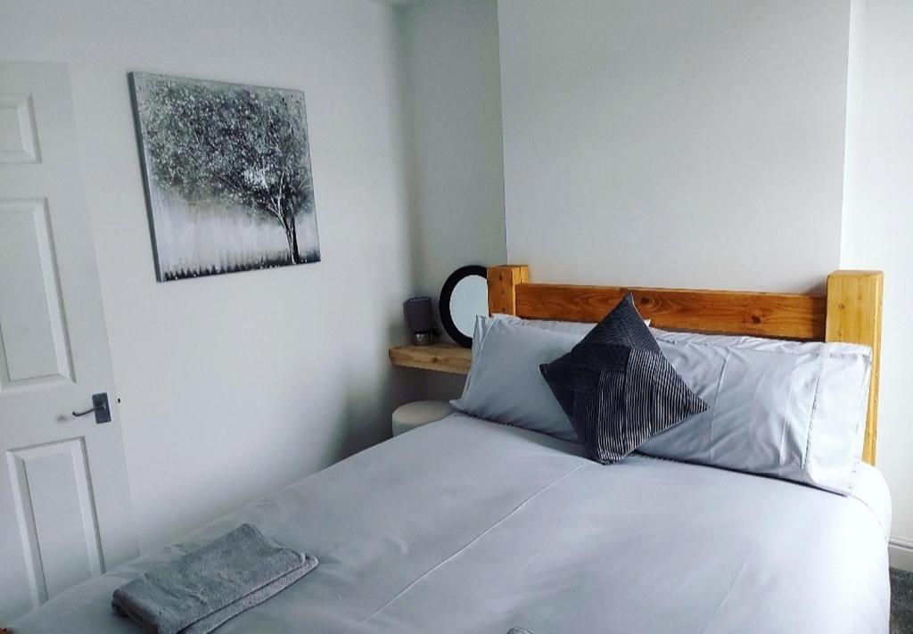 a bedroom with a white bed with a wooden headboard at The Stone House II in Nottingham