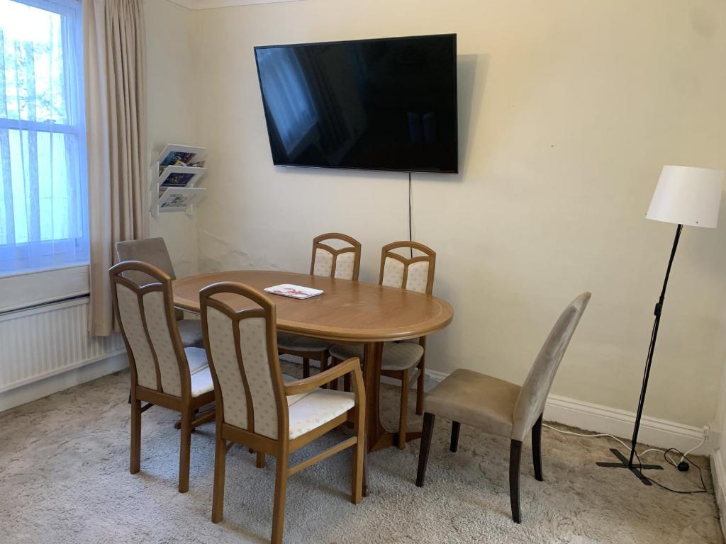 a dining room table with chairs and a television on the wall at O'Reilly's Holiday House in Bath