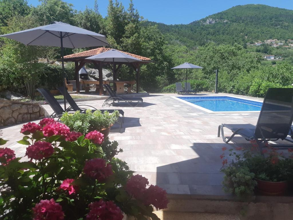 a patio with a pool and umbrellas and flowers at Apartment Opatija Lovran in Lovran