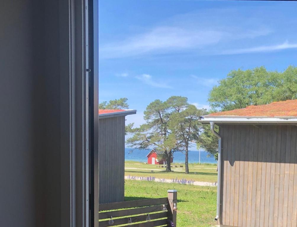 uma janela com vista para um campo e um celeiro vermelho em Gotland Tofta, Stuga med superläge! Havsutsikt på Tofta strand mindre än 10 minuter till en av Sveriges högst rankade golfbana! em Visby
