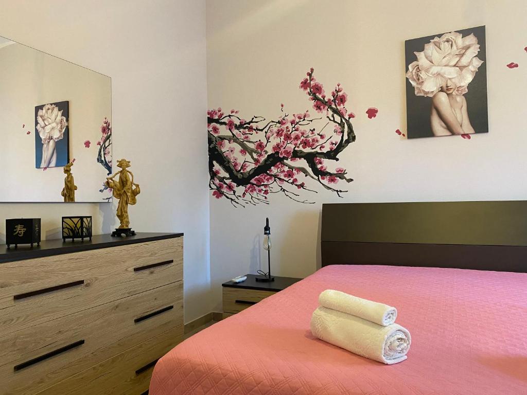 a bedroom with a pink bed and a dresser at La Casa di Zia Ninì in Villaggio Pirandello