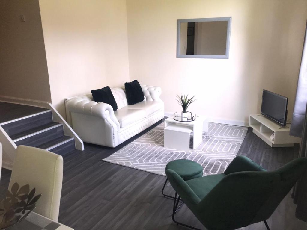 a living room with a white couch and chairs at Vogue Apartments in Glasgow