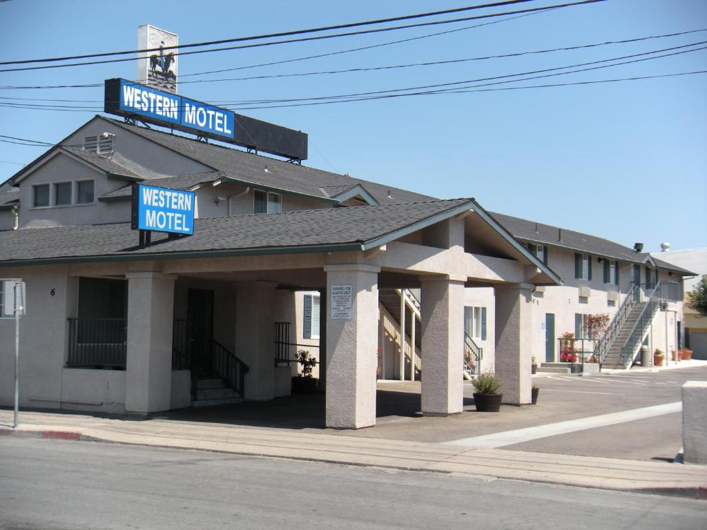 a hotel with two blue signs on top of it at Western Motel in Salinas