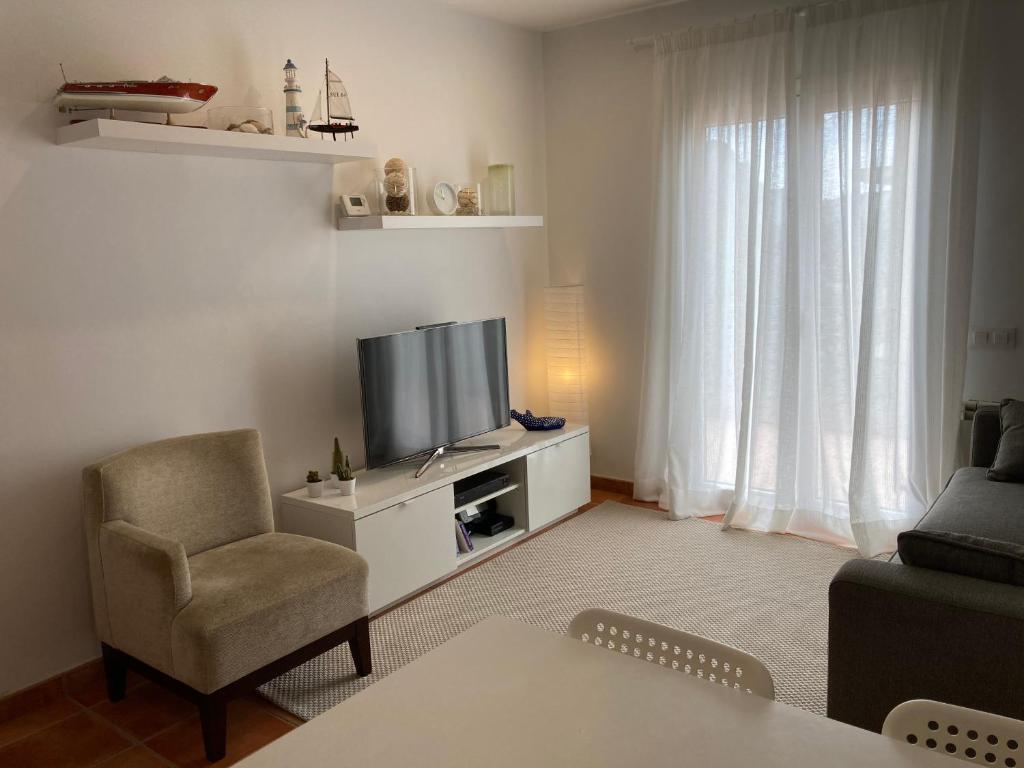 uma sala de estar com uma televisão e uma cadeira em Rascassa em Llafranc