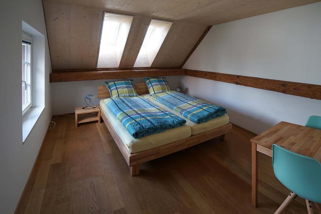 a bedroom with a bed and a table and windows at Bed and Breakfast Wegmann in Andelfingen