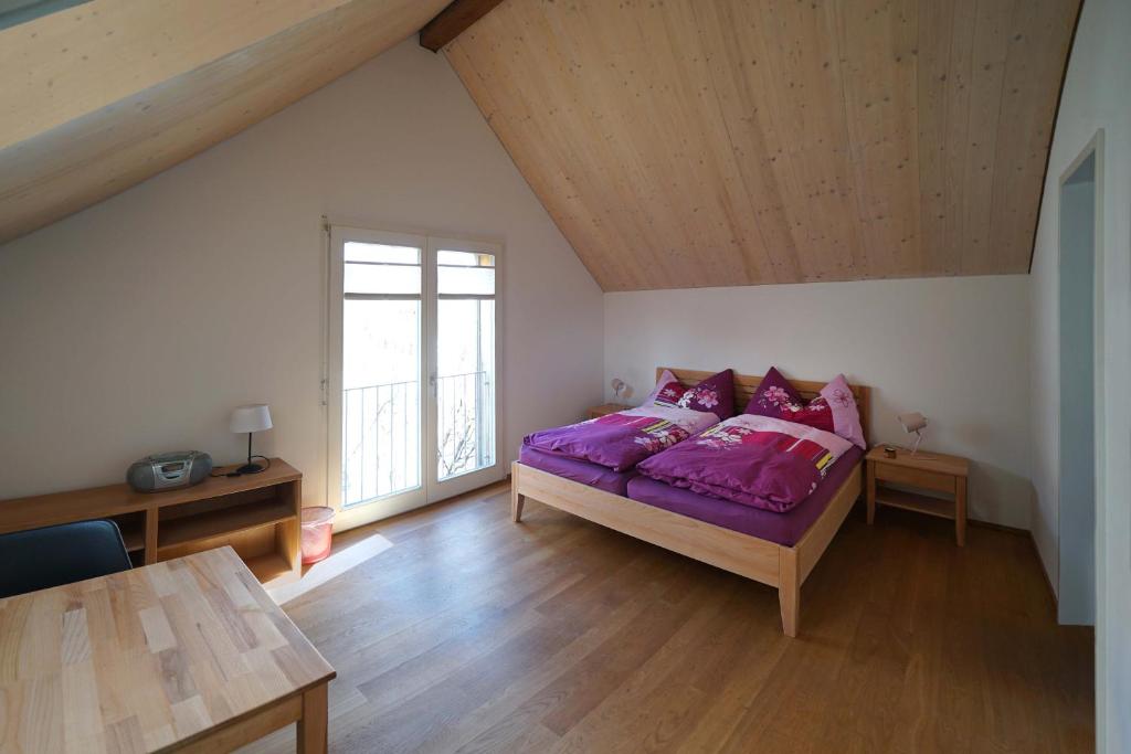 a bedroom with a purple bed and a window at Bed and Breakfast Wegmann in Andelfingen