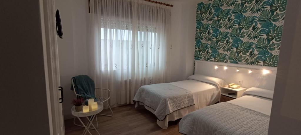 a small room with two beds and a window at Hostal Linar in A Coruña