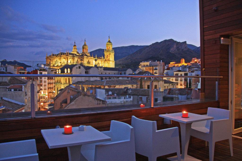 a balcony with tables and chairs and a view of a city at Hotel Xauen in Jaén