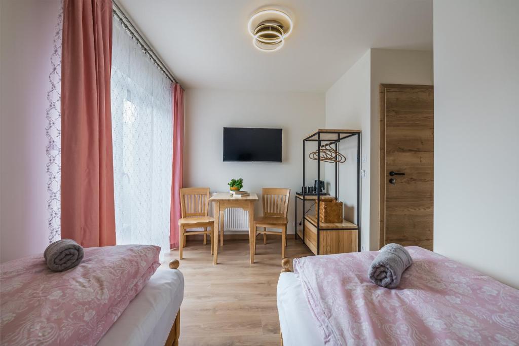 sypialnia z 2 łóżkami, stołem i telewizorem w obiekcie Willa Cichosza - wygodne i nowoczesne pokoje, 800m do centrum tuż przy szlakach pieszych i rowerowych oraz stokach narciarskich w mieście Szczawnica