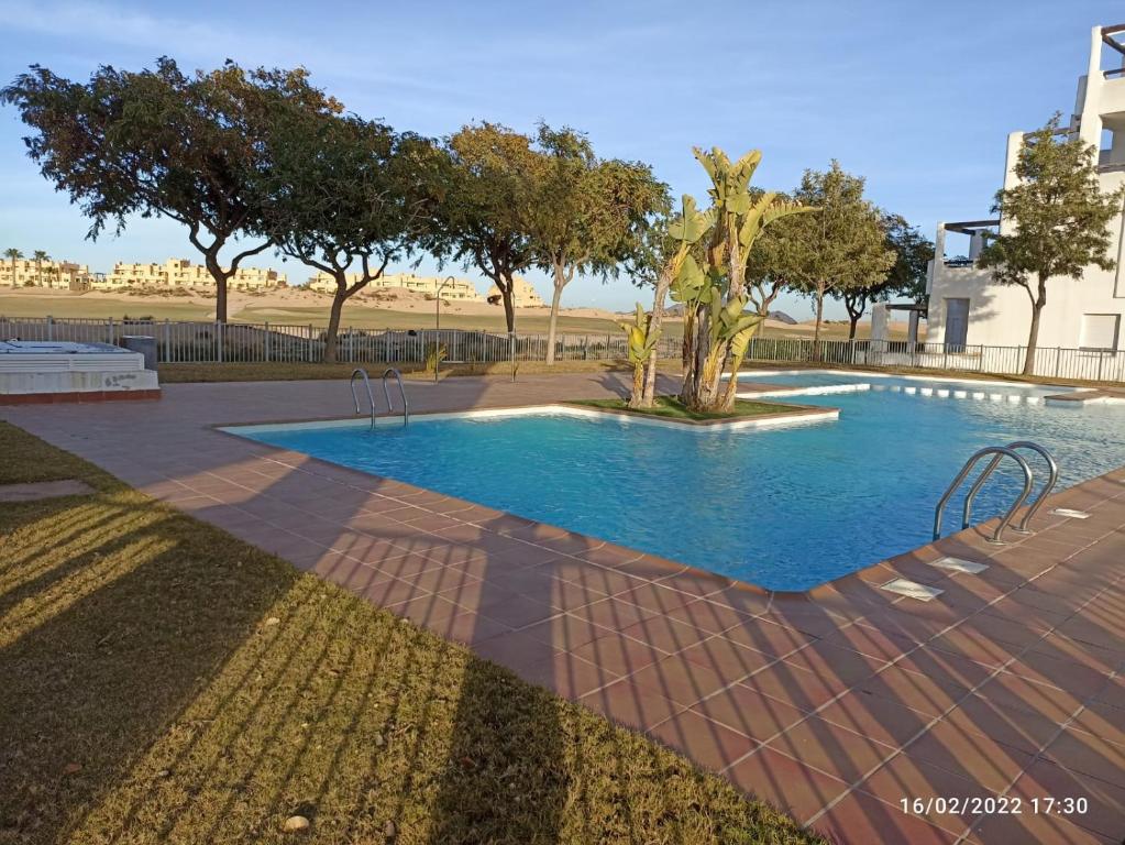 uma piscina no meio de um parque com árvores em Fabuloso Atico En Terrazas De La Torre em Roldán