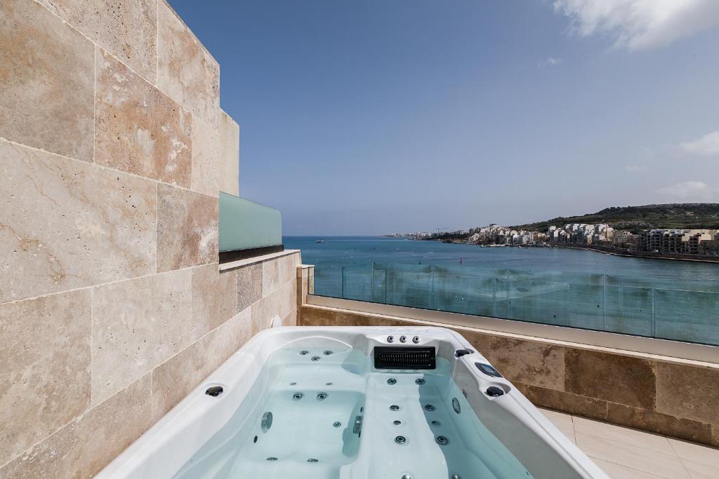 a bath tub on a balcony with a view of the water at Dearborn Seafront in St Paul's Bay