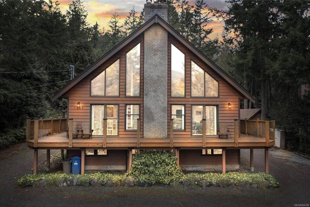 een groot houten huis met een groot terras bij Chalet Style Cottage near Shawnigan Lake in Shawnigan Lake