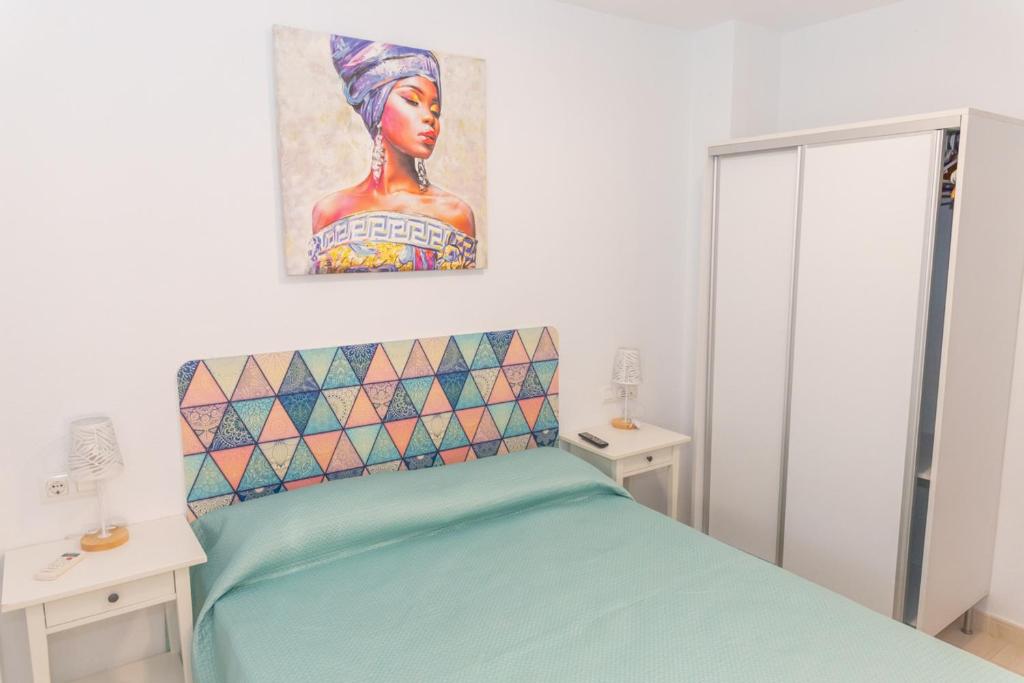 - une chambre avec un lit et une peinture murale dans l'établissement Duplex Sereno 6 - Piscina, Garaje, Jardín y Playa, à Los Caños de Meca