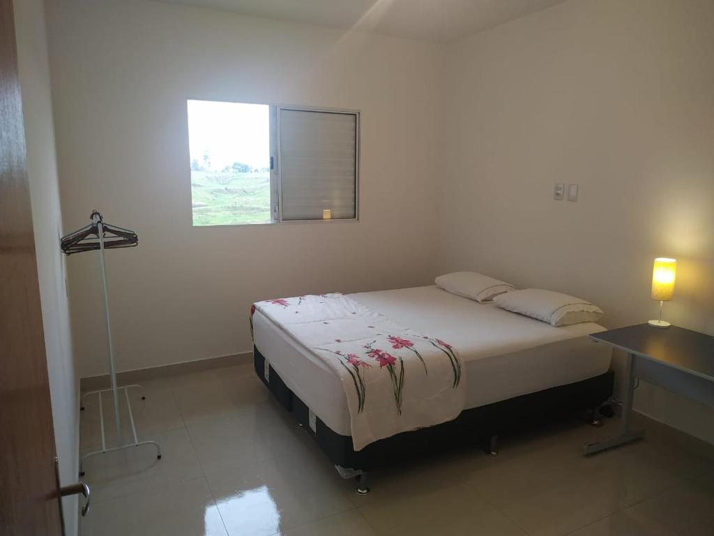 a white bedroom with a bed and a window at Acomodação corporativa: casa residencial recém-construída in Itatiba