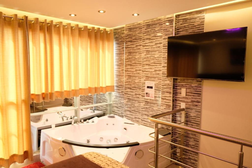 a bathroom with two sinks and a flat screen tv at Hotel Puma'r Tacna in Tacna