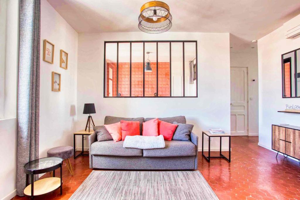 salon z szarą kanapą i czerwonymi poduszkami w obiekcie SUITE LAMARTINE w miejscowości Saint-Raphaël