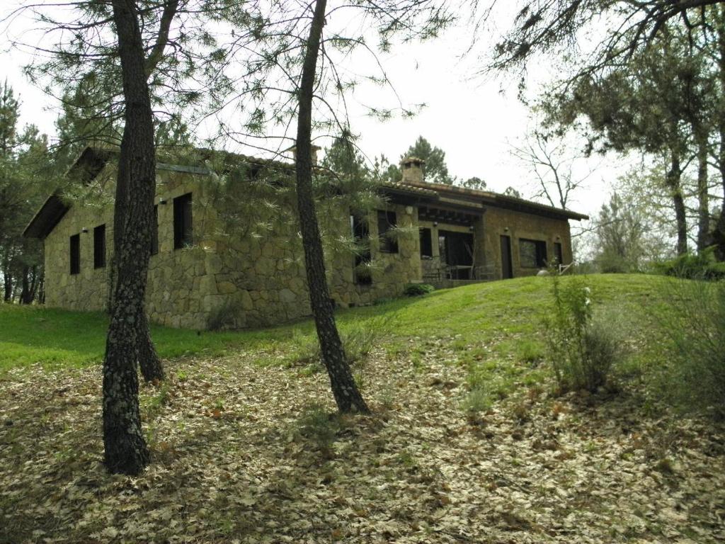 uma antiga casa de pedra numa colina com árvores em La Gurriata de La Vera em Villanueva de la Vera