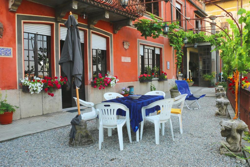 a table and chairs and an umbrella in front of a building at B&B La Finestra sul Fiume in Vaprio dʼAdda