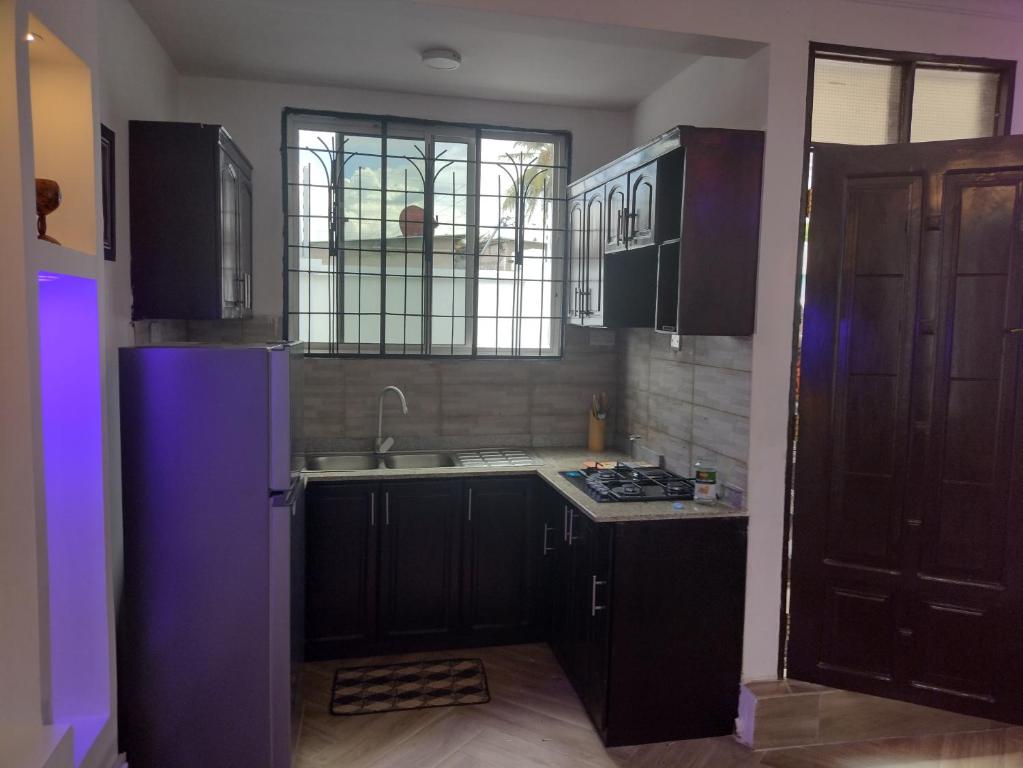 uma cozinha com armários pretos, um lavatório e uma janela em Mkamiti Villa - Airport Hotel em Dar es Salaam
