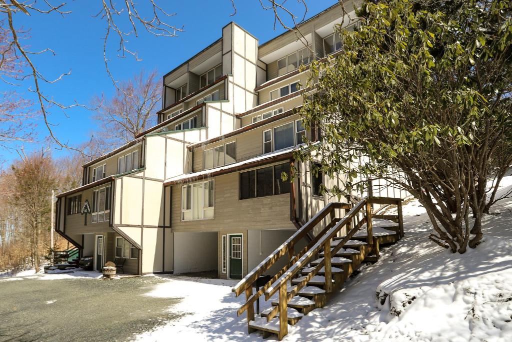an apartment building in the snow with a staircase at Beech Manor by VCI Real Estate Services in Beech Mountain